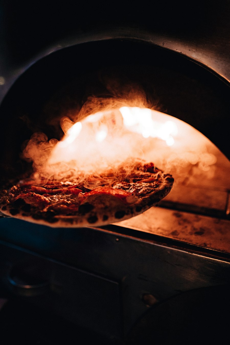 Pizza im heißen Ofen, dahinter Flammen
